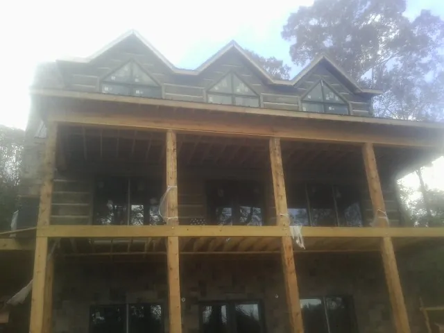 Dormers and porch framing on a large log home under construction — Roof Coating work by our crew in Wilmot